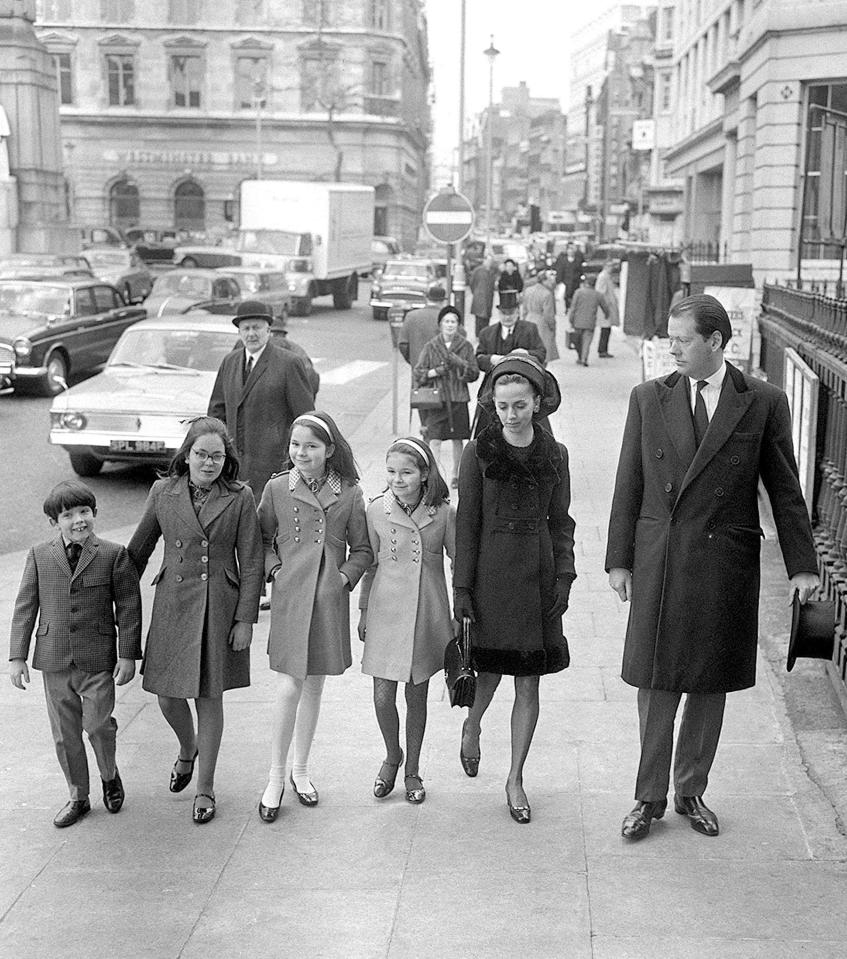 a black and white photo of a family walking down a street