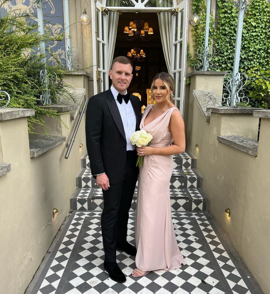 a man in a tuxedo and a woman in a pink dress pose for a picture