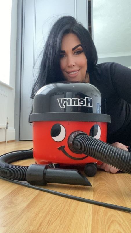 a woman laying on the floor next to a henry vacuum cleaner