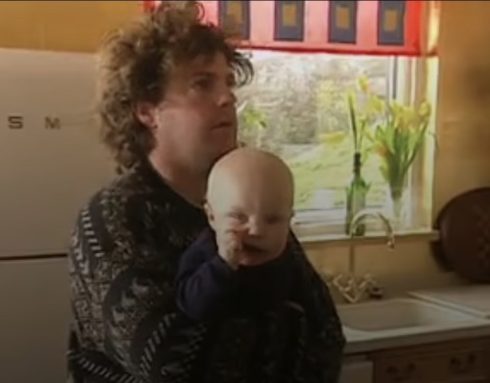 a woman is holding a baby in front of a smeg refrigerator