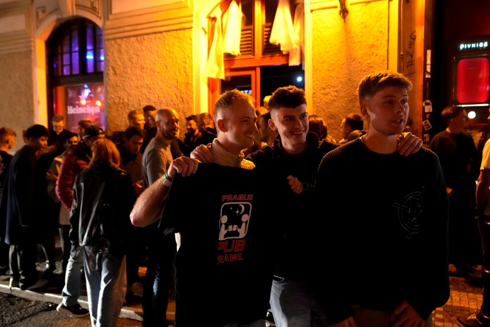 A group of tourists stand in line outside a bar as they attend a pub crawl tour in downtown Prague days after the ban was announced