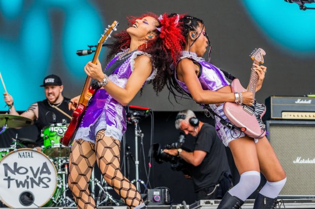 two women playing guitars in front of a drum that says natal nova twins