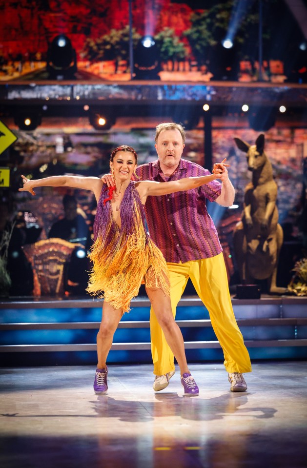 a man and a woman are dancing on a stage with a kangaroo in the background