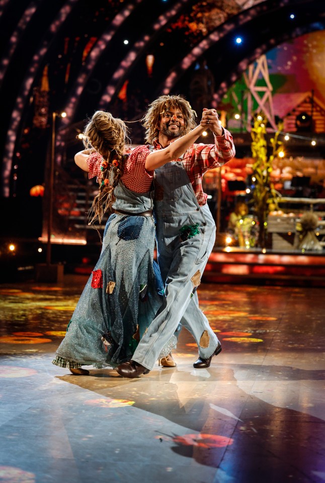 a man and woman in overalls are dancing on a stage