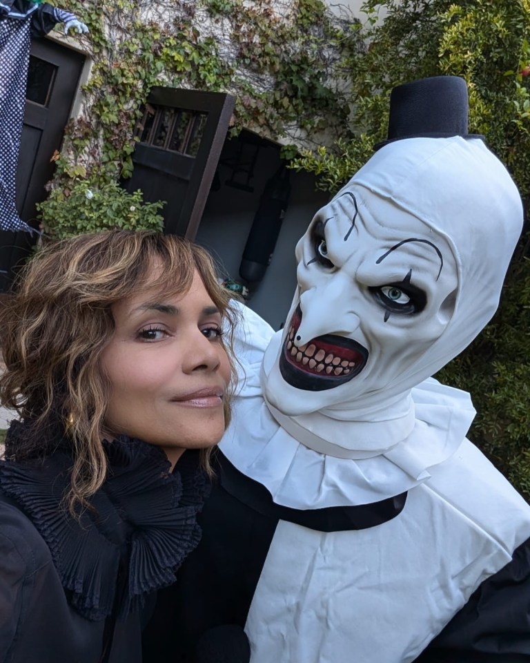 a woman stands next to a clown in a white mask