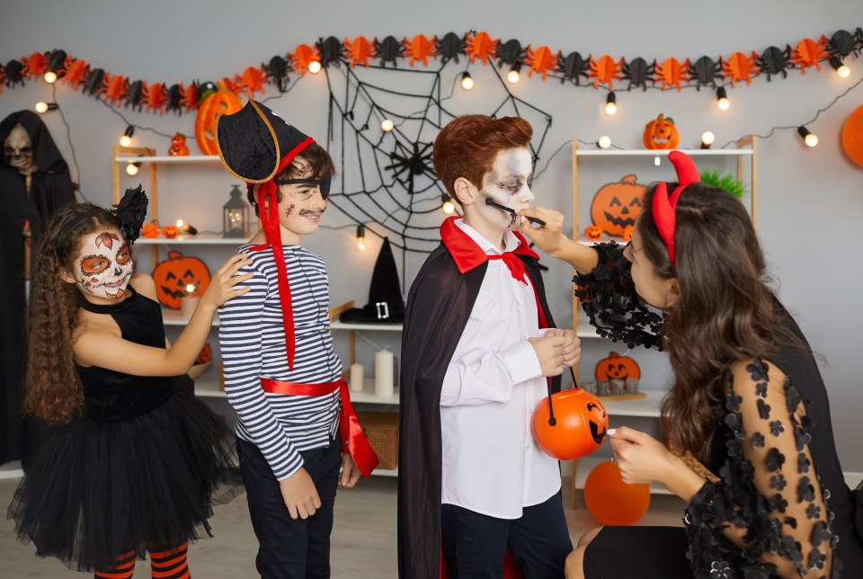 a woman and two children in halloween costumes are walking down a road