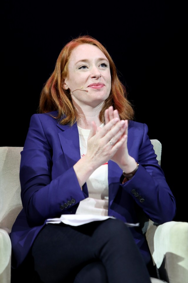 a woman in a blue jacket is clapping her hands