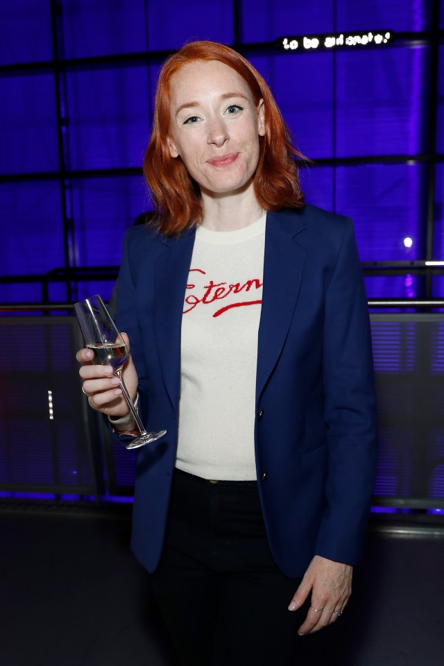 a woman with red hair is holding a glass of wine