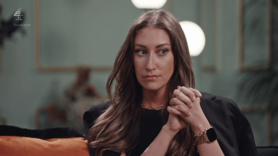 a woman is sitting on a couch with her hands folded in front of her face