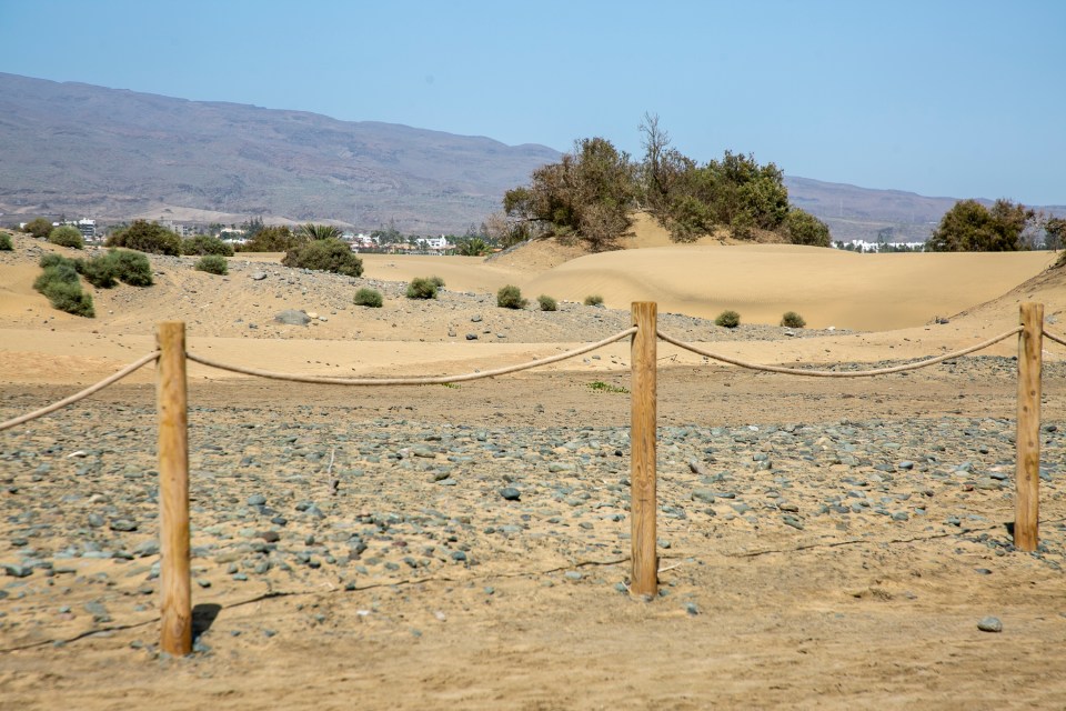 a rope fence in the desert with mountains in the background