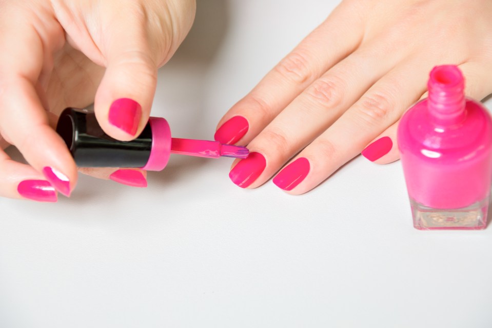 a woman is applying pink nail polish to her nails