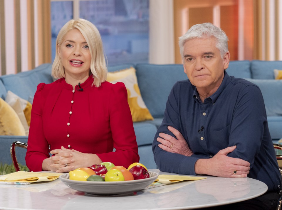 holly and phillip sit at a table with a bowl of fruit