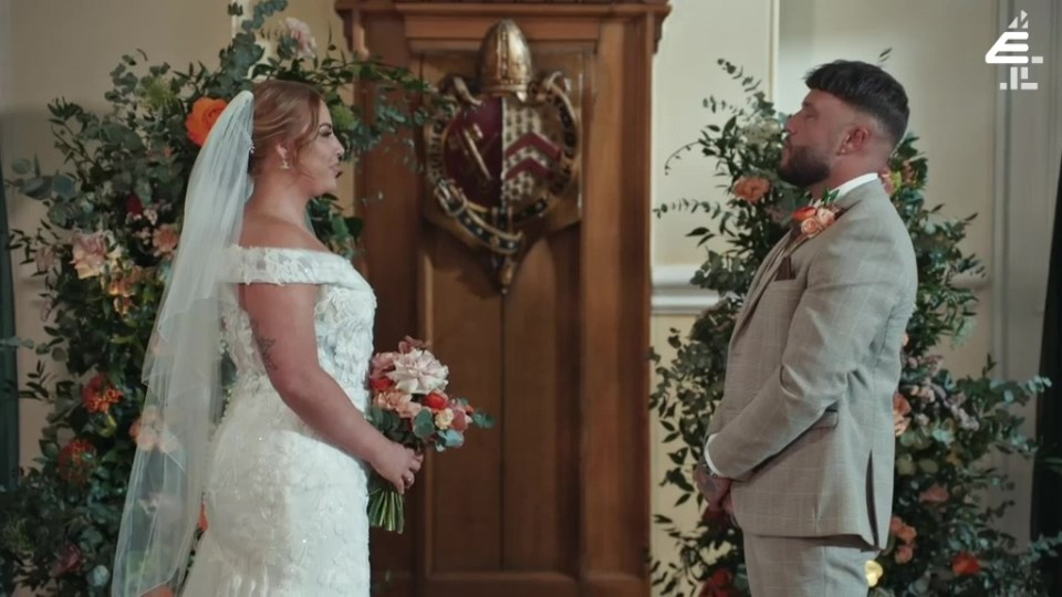 a bride and groom are standing in front of a coat of arms