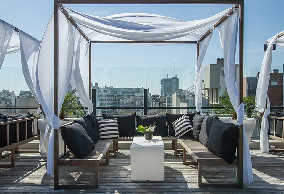 a patio area with black and white pillows and a canopy