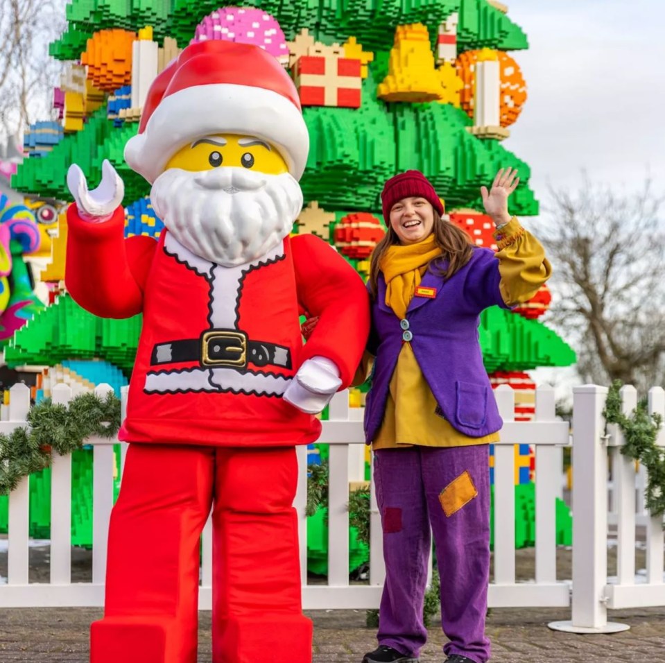 a woman in a purple outfit stands next to a santa claus statue