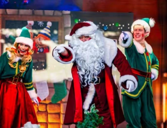 a group of people dressed as santa claus and elves are dancing on a stage .