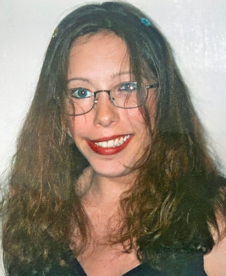 a woman wearing glasses and red lipstick smiles for the camera