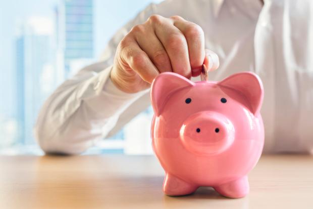 a person putting a coin into a pink piggy bank