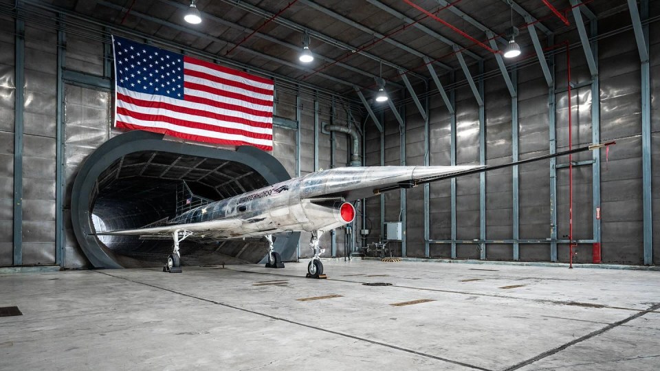 an american flag hangs above a plane in a hangar