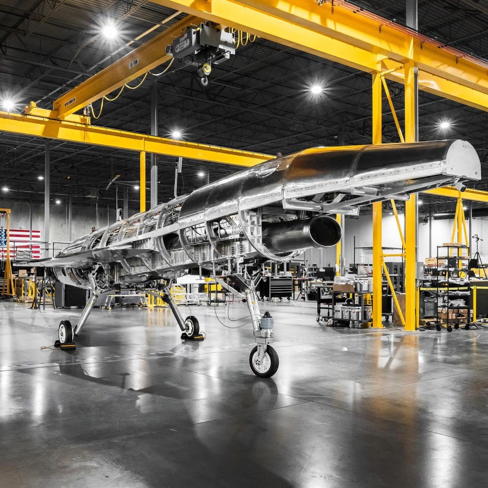 an airplane is being assembled in a warehouse with a yellow crane