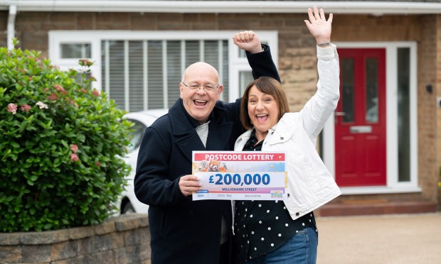 a man and woman holding a postcode lottery ticket