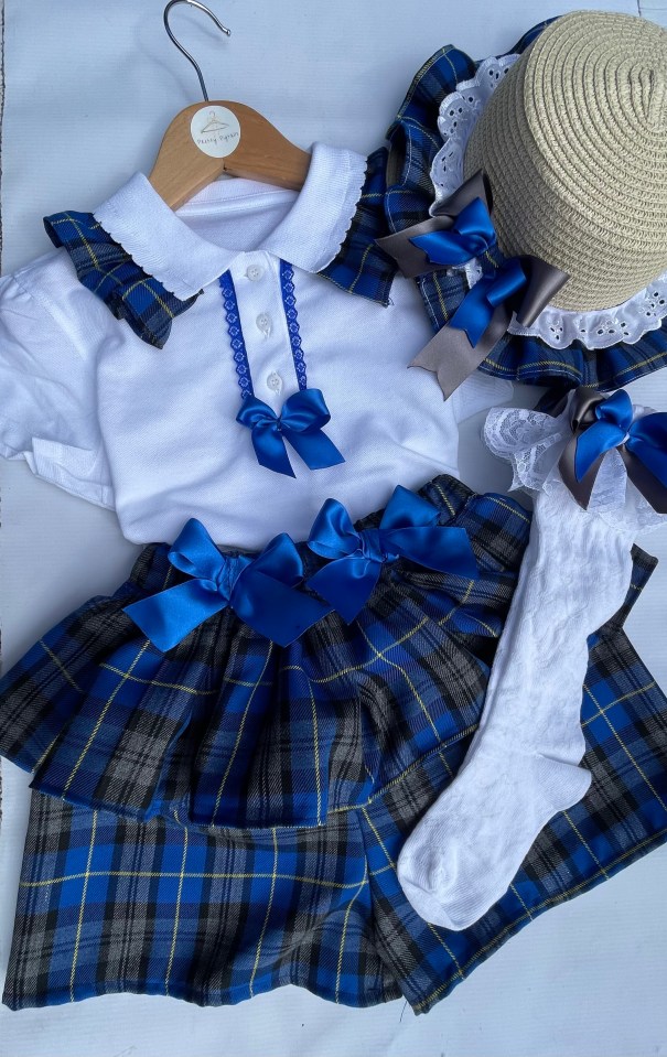 a child 's plaid outfit is hanging on a wooden hanger