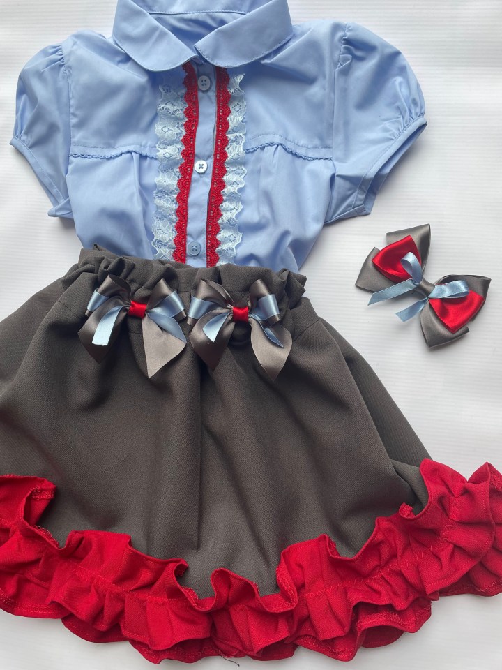 a girl wearing a blue shirt and a skirt with red ruffles