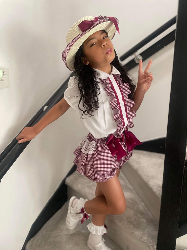 a little girl wearing a straw hat giving a peace sign