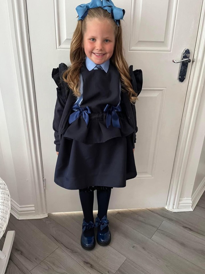 a little girl wearing a black dress with blue bows