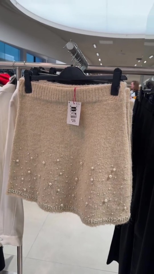 a white skirt with pearls on it is hanging on a rack