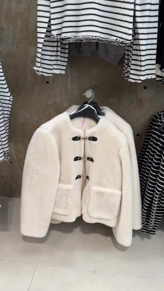 a white jacket is hanging on a hanger in a store