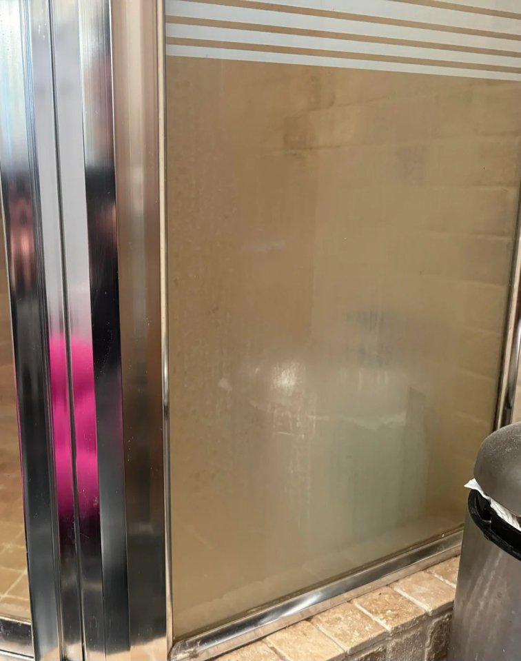 a dirty shower door with a stainless steel frame