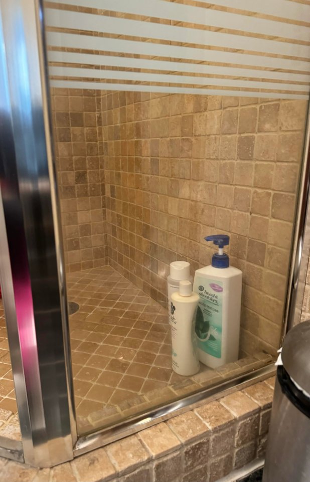 a bottle of pantene shampoo sits in a shower