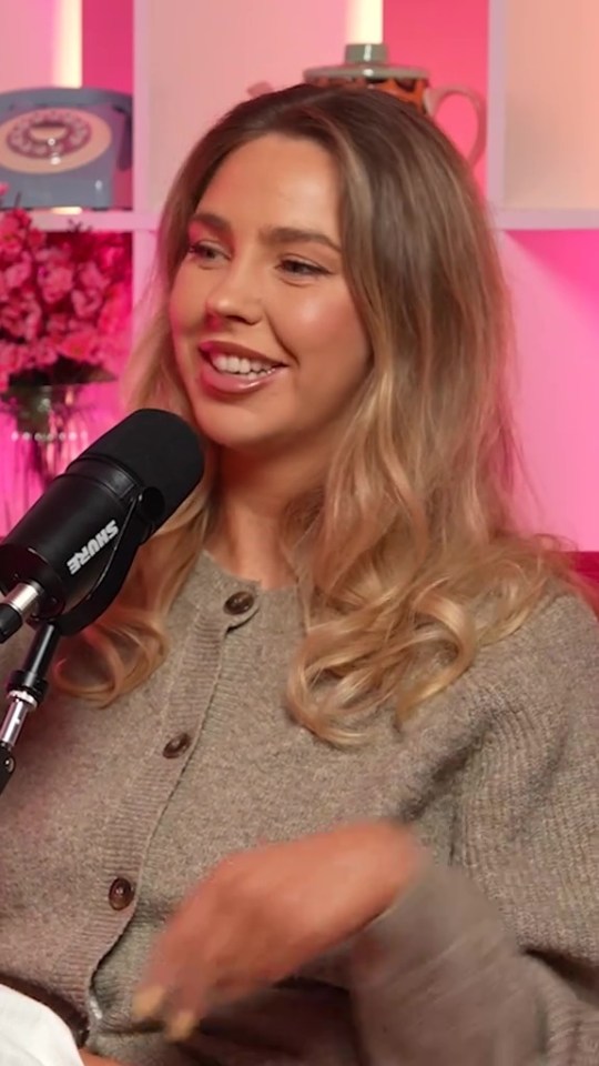 a woman is smiling in front of a shure microphone