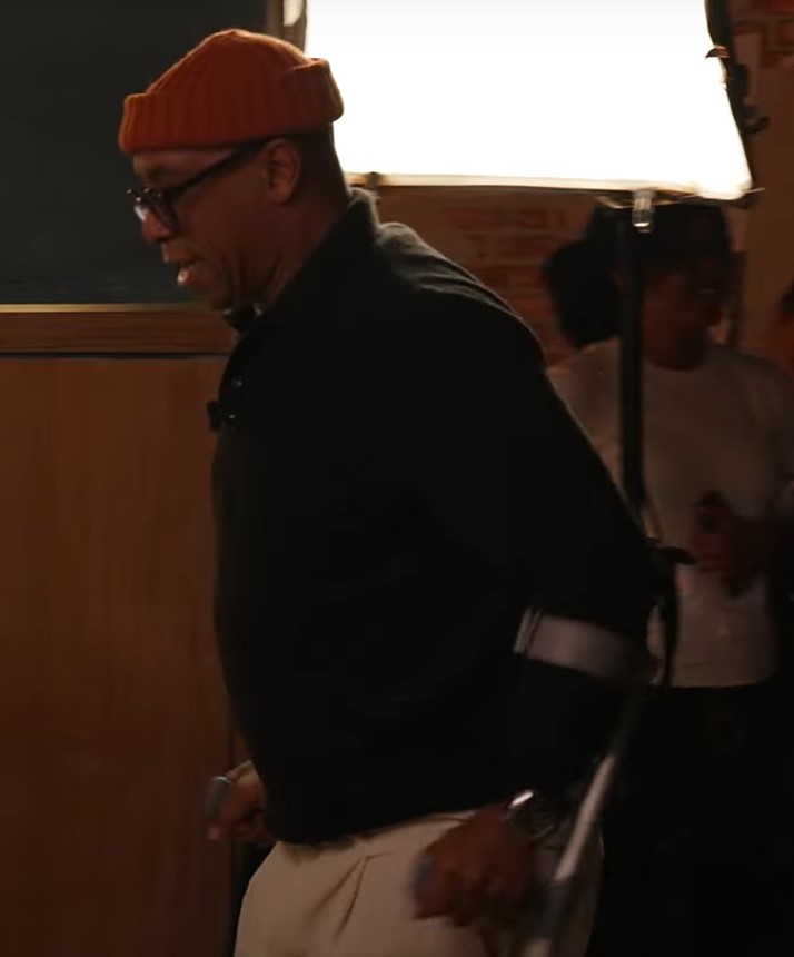 a man wearing an orange beanie and glasses is standing in front of a light