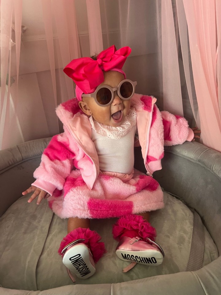 a baby wearing a pink outfit and moschino shoes