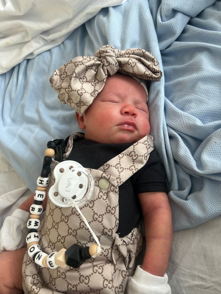 a baby wearing a gucci outfit has a pacifier attached to it