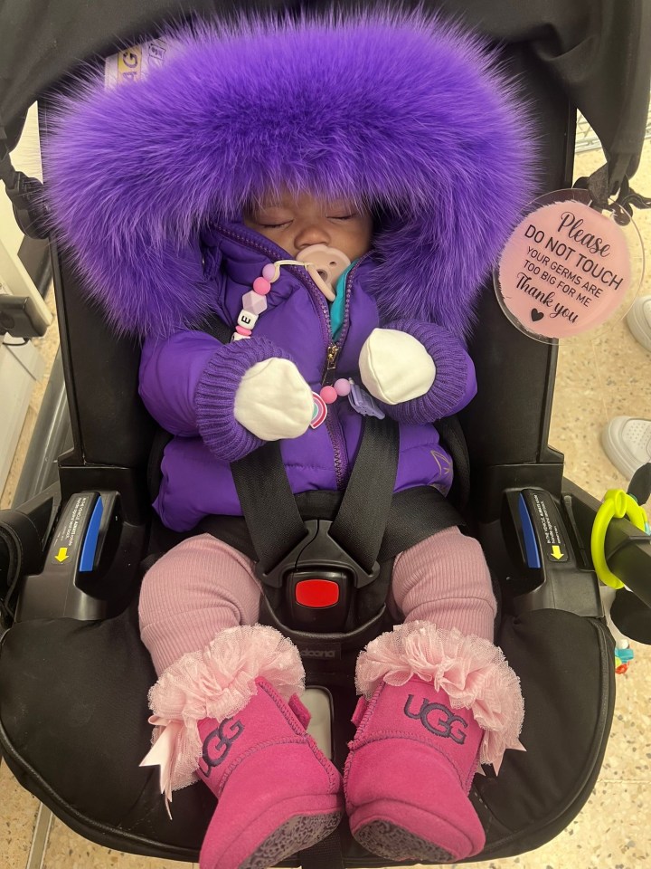 a baby wearing a purple jacket and pink ugg boots sits in a car seat