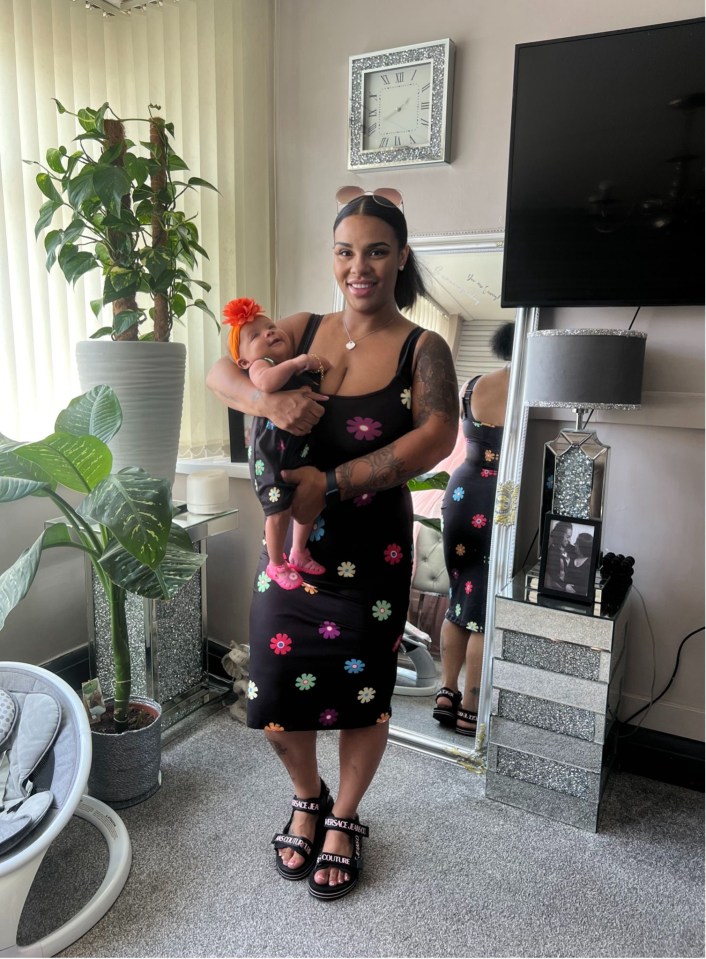 a woman holding a baby in front of a clock that says xii on it