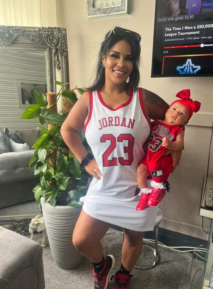 a woman in a jordan 23 jersey holds a baby