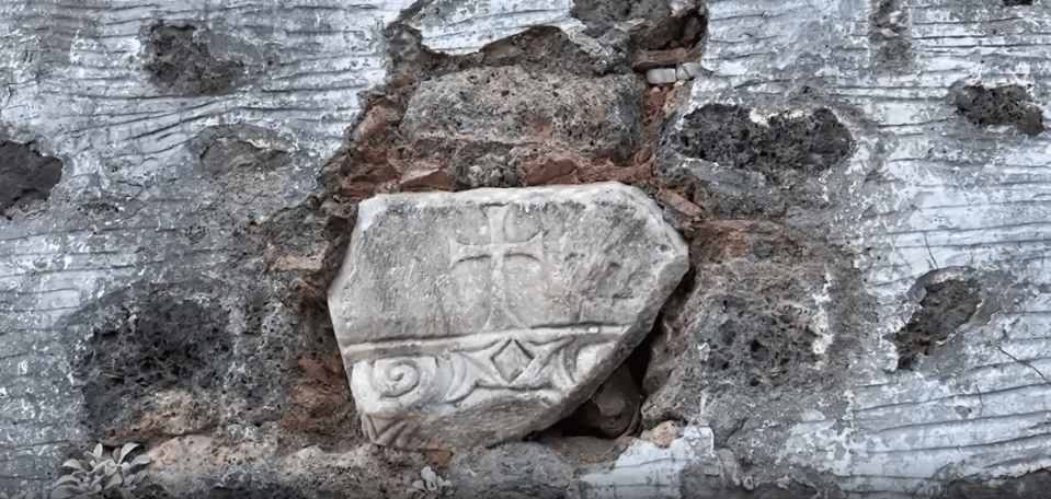 a piece of stone with a cross and the letter o on it