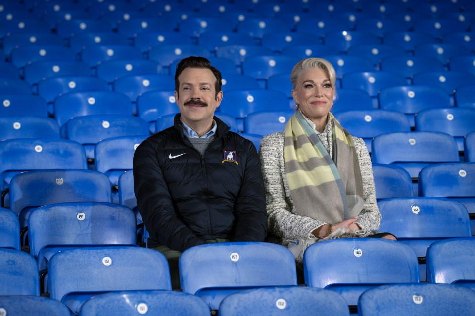 a man and a woman are sitting in a stadium watching a game