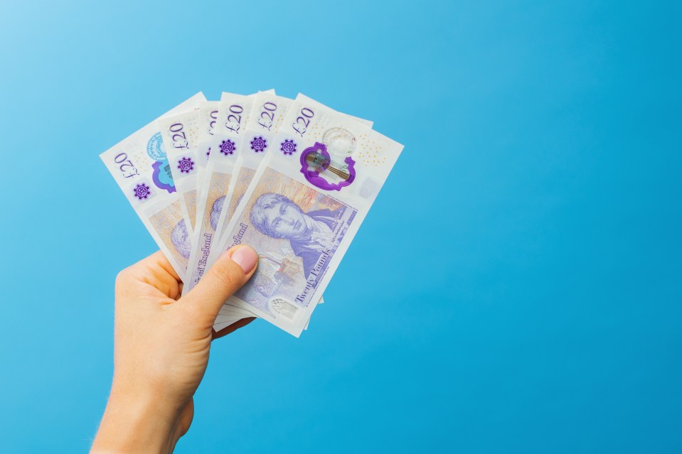 a hand holding a fan of twenty pound notes