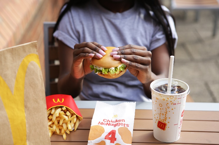 a woman is eating a mcdonald 's chicken mcnuggets sandwich