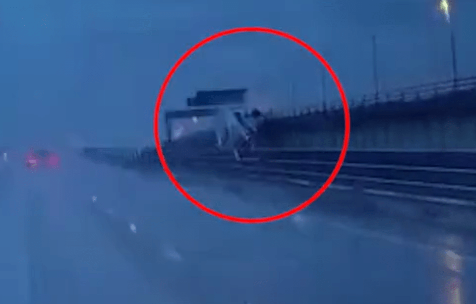 a lorry is going over a bridge in the rain .