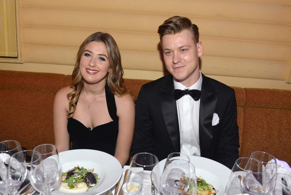 a man and a woman sit at a table with plates of food and wine glasses