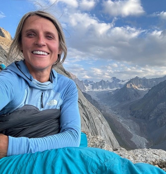 a woman in a north face sleeping bag smiles for the camera