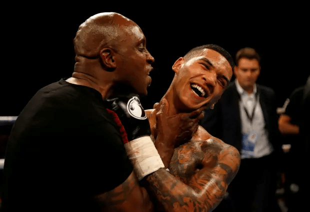 a man in boxing gloves holds another man in a boxing ring