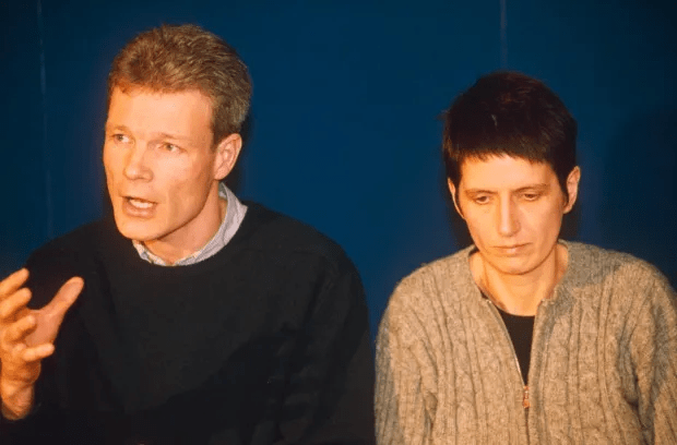 a man and a woman are sitting in front of a blue wall