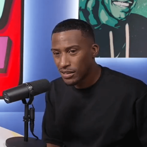 a man in a black shirt is sitting in front of a microphone